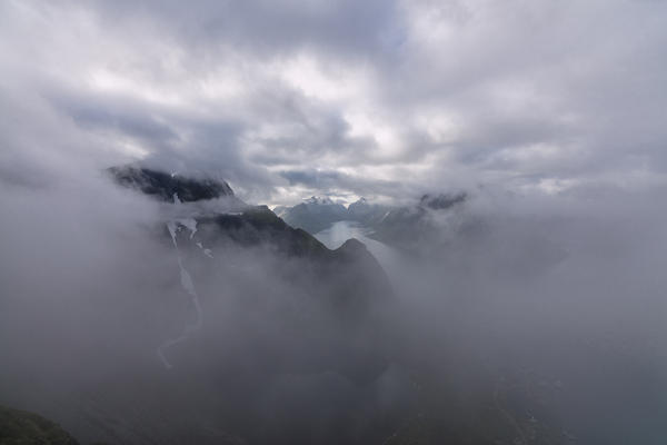 Top view of sea framed by silhouettes of peaks covered by clouds and mist Reinebringen Moskenes Lofoten Islands Norway Europe