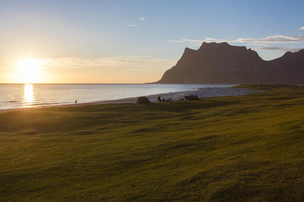 Camping tents on green meadows lighted up by midnight sun reflected in sea Uttakleiv Lofoten Islands Northern Norway Europe