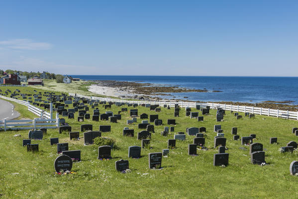 Cemetary in the green meadows surrounded by blue sea Vaeroy Island Nordland county Lofoten archipelago Norway Europe