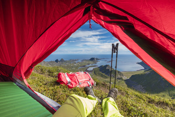 Tent and hiker on mountain top overlooking the sea Sorland Vaeroy Island Nordland county Lofoten archipelago Norway Europe