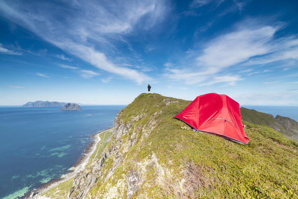 Tent and hiker on mountain ridge overlooking the sea Sorland Vaeroy Island Nordland county Lofoten archipelago Norway Europe