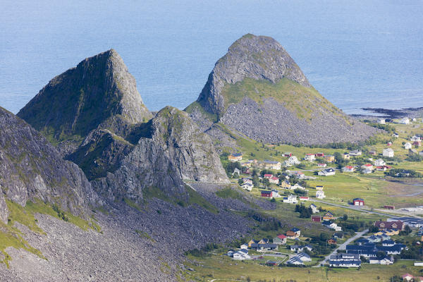 Rocky peaks frame the village of Sorland surrounded by sea Vaeroy Island Nordland county Lofoten archipelago Norway Europe