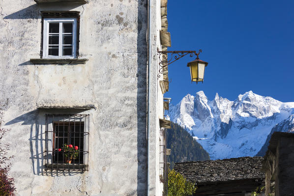 Typical alpine house and street lantern frame the snowy peaks Soglio Bregaglia Valley canton of Graubünden Switzerland Europe