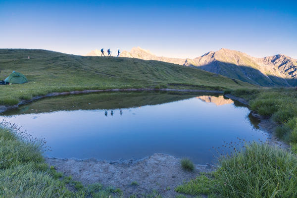 Silhouettes of hikers are reflected in the lake with Mont De La Saxe on the background Courmayeur Aosta Valley Italy Europe