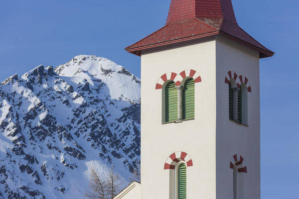 Bell tower of the alpine church framed by snowy peaks Maloja Bregaglia Valley Canton of Graubünden Engadine Switzerland Europe