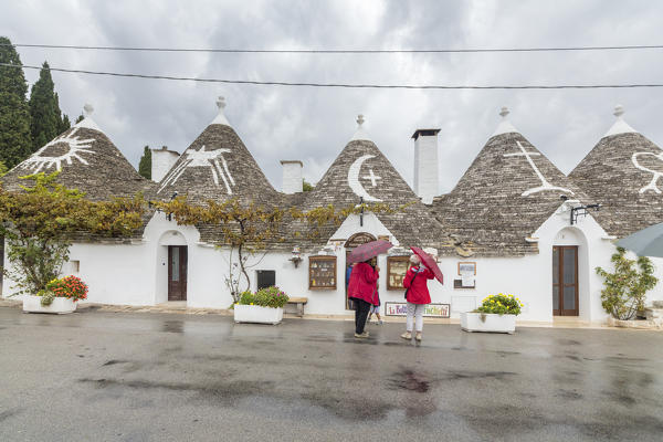 Tourists admire the typical Trulli built with dry stone with a conical roof Alberobello province of Bari Apulia Italy Europe