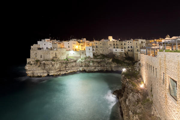 Dusk lights on the old town perched on the rocks surrounded by clear sea Polignano a Mare province of Bari Apulia Italy Europe