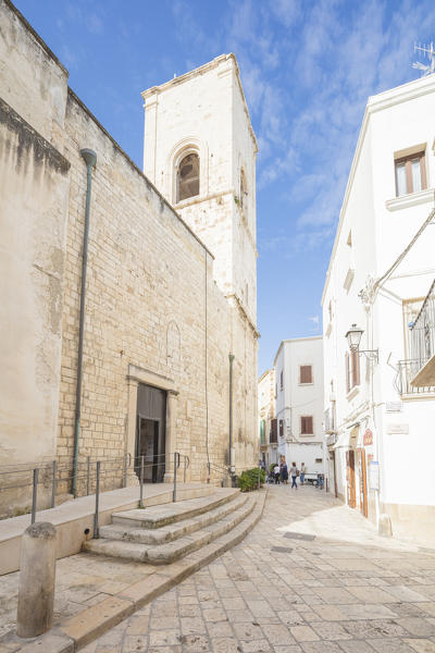 Bell tower and typical alley of white houses in the old town Polignano a Mare province of Bari Apulia Italy Europe