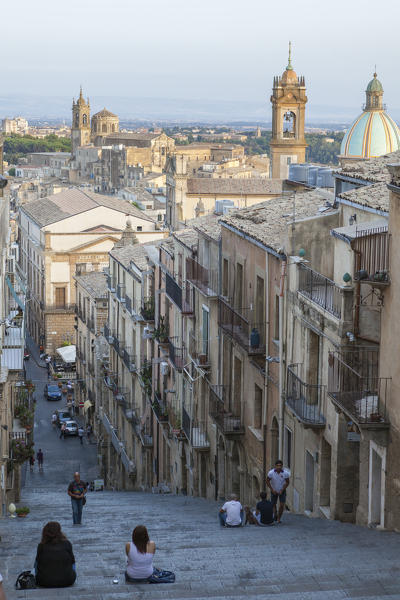 Tourists on flight of steps admire the old town and dome of cathedral of Caltagirone province of Catania Sicily Italy Europe