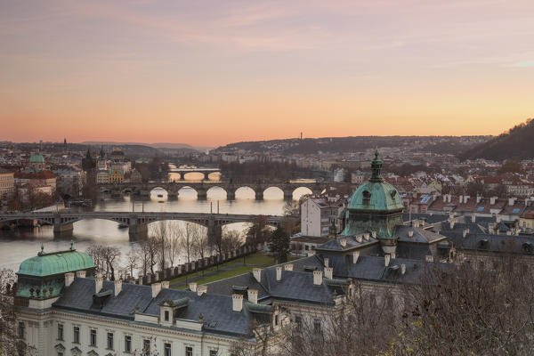Pink sky on historical bridges and buildings reflected on Vltava (Moldava) river at sunset Prague Czech Republic Europe
