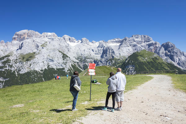 People in the green meadows admire the rocky peaks Doss Del Sabion Pinzolo Brenta Dolomites Trentino Alto Adige Italy Europe