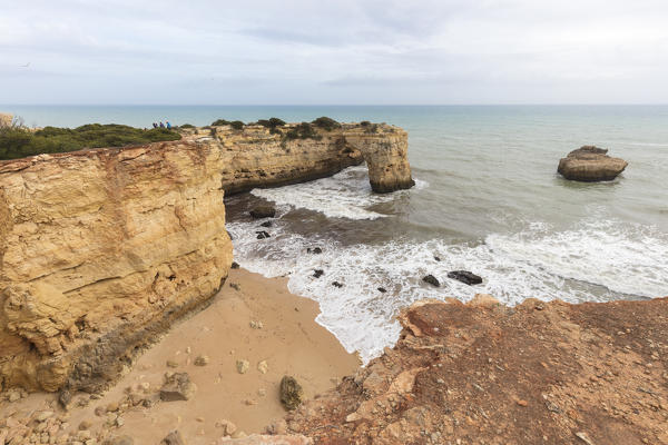 Waves crashing on the sand beach surrounded by cliffs Albandeira Lagoa Municipality Algarve Portugal Europe