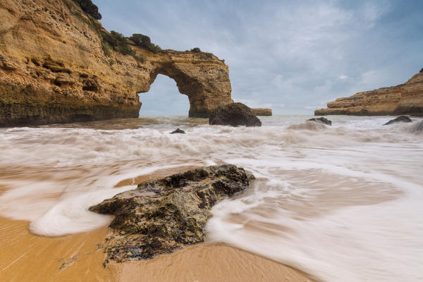 Waves crashing on the sand beach surrounded by cliffs Albandeira Lagoa Municipality Algarve Portugal Europe