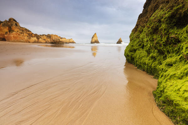 Rocks surrounding the sandy beach are reflected in the clear water Albandeira Lagoa Municipality Algarve Portugal Europe