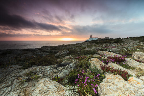 Pink sky at sunset frames the lighthouse overlooking the Atlantic Ocean Cabo De Sao Vicente Sagres Algarve Portugal Europe