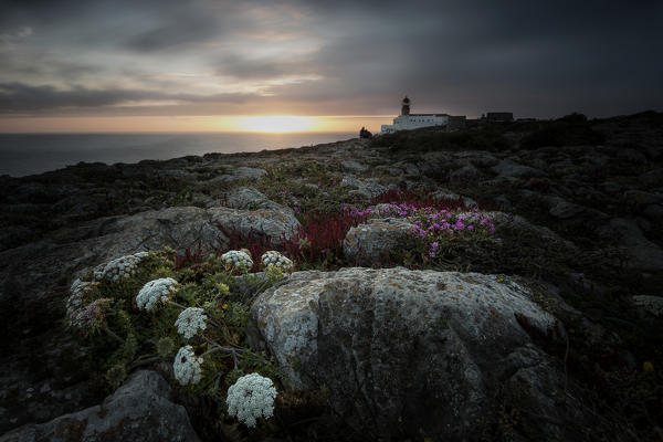 The last lights of sunset frame the lighthouse overlooking the Atlantic Ocean Cabo De Sao Vicente Sagres Algarve Portugal Europe