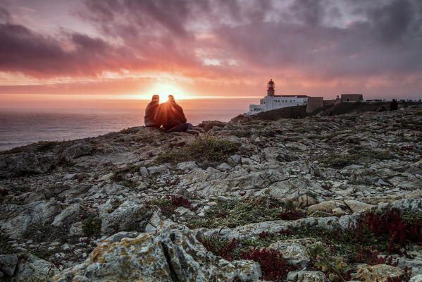 Pink sky at sunset frames the lighthouse overlooking the Atlantic Ocean Cabo De Sao Vicente Sagres Algarve Portugal Europe