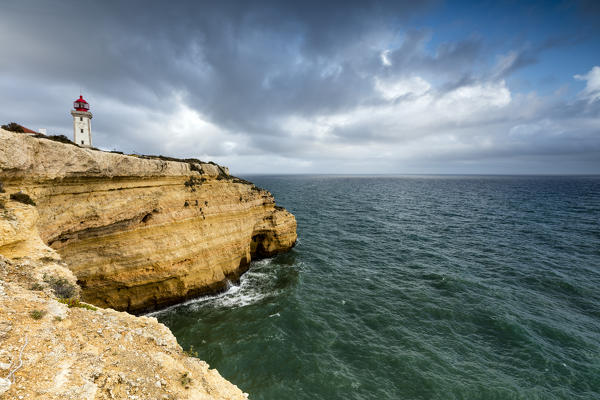 Clouds frame the lighthouse on cliffs overlooking the Atlantic Ocean Carvoeiro Lagoa Municipality Algarve Portugal Europe