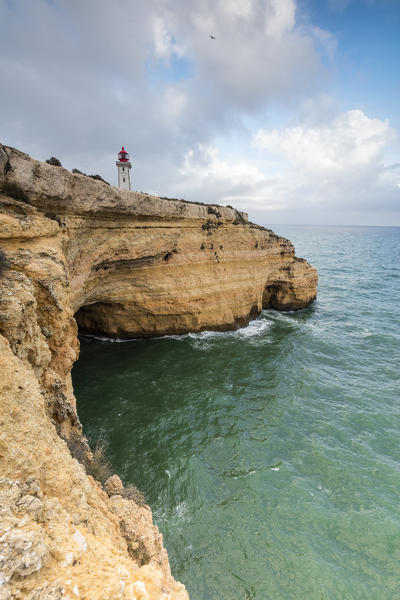 The lighthouse on cliffs frames the turquoise water of the Atlantic Ocean Carvoeiro Lagoa Municipality Algarve Portugal Europe