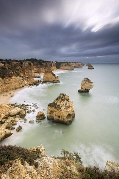 Dark clouds on cliffs framed by the turquoise ocean Praia da Marinha Caramujeira Lagoa Municipality Algarve Portugal Europe