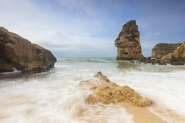 Waves crashing on the sand beach surrounded by cliffs Praia da Marinha Caramujeira Lagoa Municipality Algarve Portugal Europe