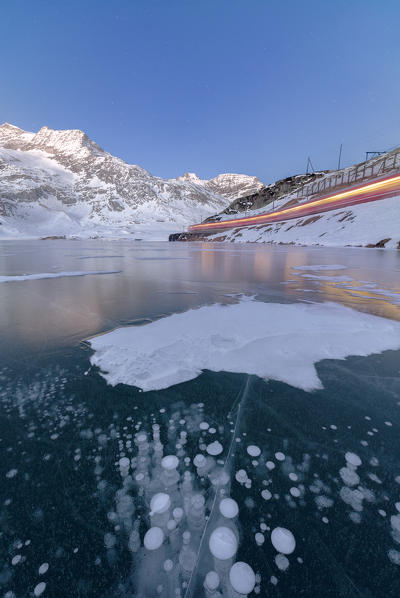 The Bernina Express train runs beside the frozen Lago Bianco Bernina Pass canton of Graubünden Engadine Switzerland Europe