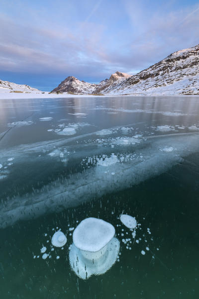 Ice bubbles frame the snowy peaks reflected in Lago Bianco Bernina Pass canton of  Graubünden Engadine Switzerland Europe