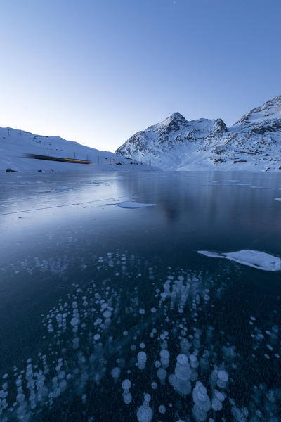 Ice bubbles frame the snowy peaks reflected in Lago Bianco Bernina Pass canton of  Graubünden Engadine Switzerland Europe