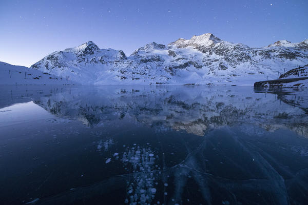 Ice bubbles frame the snowy peaks reflected in Lago Bianco Bernina Pass canton of  Graubünden Engadine Switzerland Europe