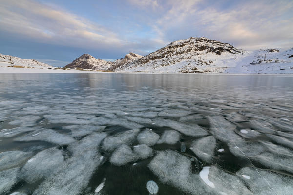 The frozen surface of Lago Bianco framed by snowy peaks Bernina Pass canton of Graubünden Engadine Switzerland Europe