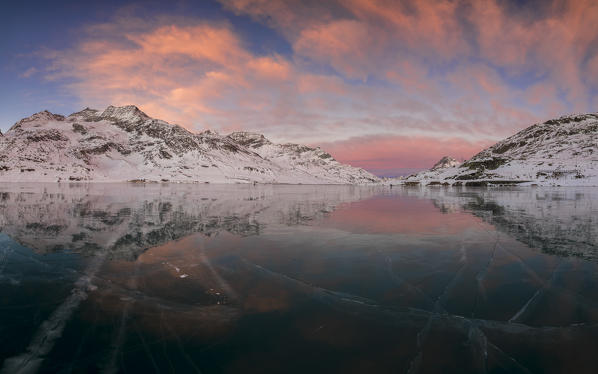 Panorama of the frozen Lago Bianco under pink clouds at dawn Bernina Pass canton of  Graubünden Engadine Switzerland Europe