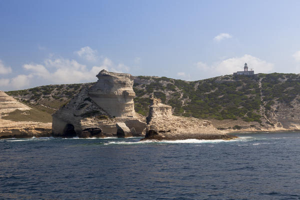 Blue sea frames granite cliffs and lighthouse perched on the hill Lavezzi Islands Bonifacio Corsica France Europe
