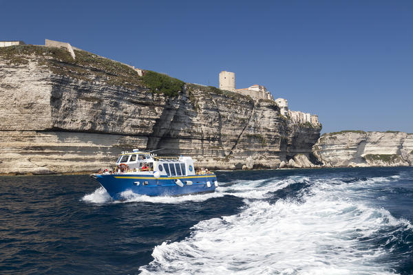 A tourist boat framed by the ancient village perched on the white cliffs Lavezzi Islands Bonifacio Corsica France Europe