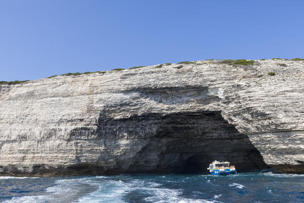 A tourist boat framed by granite white cliffs and sea caves Lavezzi Islands Bonifacio Corsica France Europe