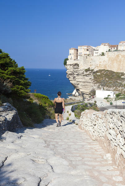 Tourists admire the medieval old town perched on top of cliffs overlooking the blue sea Bonifacio Corsica France Europe