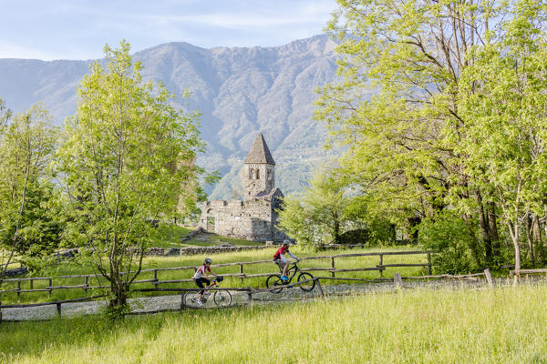 Cyclists on mountain bike around the Abbey of San Pietro in Vallate Piagno Sondrio province Valtellina Lombardy Italy Europe