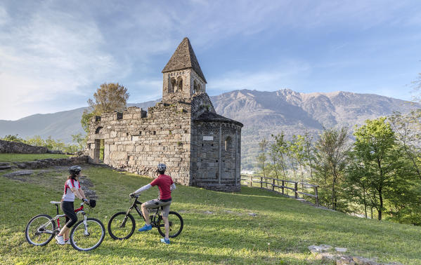 Cyclists admire the ancient Abbey of San Pietro in Vallate in spring Piagno Sondrio province Valtellina Lombardy Italy Europe