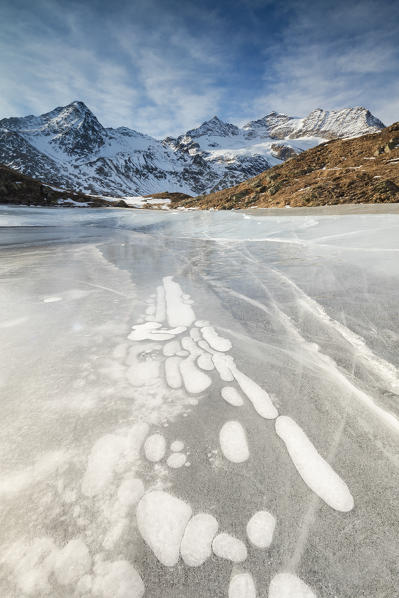Ice bubbles in the frozen Lej Nair surrounded by snowy peaks Bernina Pass Canton of Graubünden Engadine Switzerland Europe