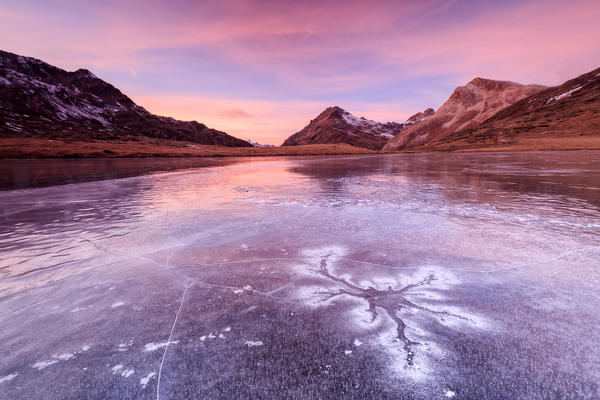 Pink sky at sunset frames the frozen surface of Lej Nair Bernina Pass Canton of Graubünden Engadine Switzerland Europe