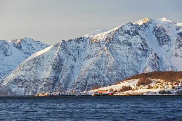 The typical fishing village of Hamnes framed by snowy peaks and the cold sea Lyngen Alps Tromsø Norway Europe