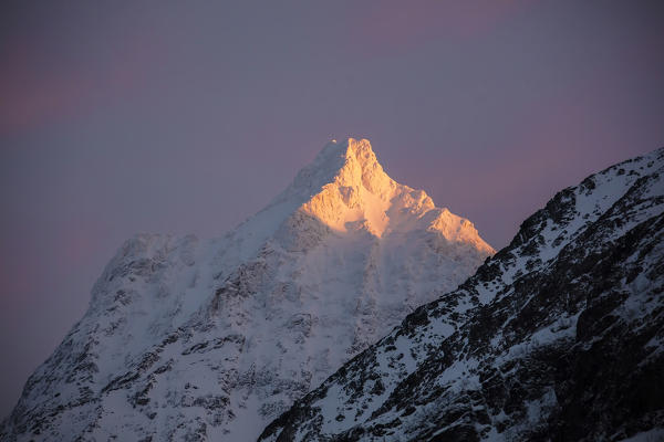 The pink light of sunrise illuminates the snowy peaks of the rocky mountains Svensby Lyngen Alps Tromsø Norway Europe