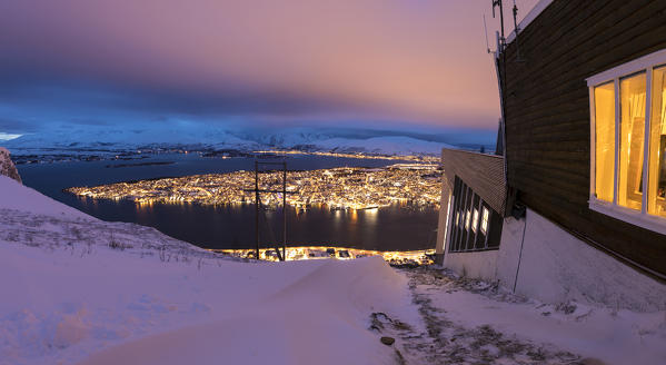 Panorama of wood chalet on mountain top reached by the Fjellheisen cable car overlooks the city of Tromsø at dusk Norway Europe
