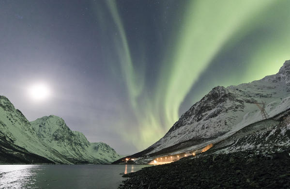 The Northern Lights and moon reflected in the sea illuminate the snowy peak of the Lyngseidet Lyngen Alps Tromsø Norway Europe