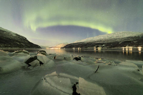 Northern Lights reflected in the cold sea frames the rocks covered with ice Manndalen Kafjord Lyngen Alps Tromsø Norway Europe