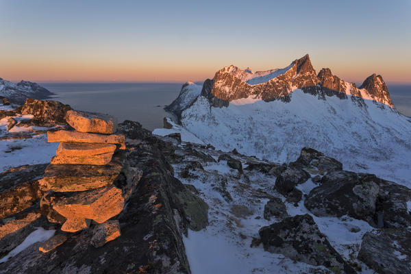 The rocky peaks of the Kongen Mountain and icy sea along the Mefjorden seen from peak Hesten at dawn Senja Tromsø Norway Europe