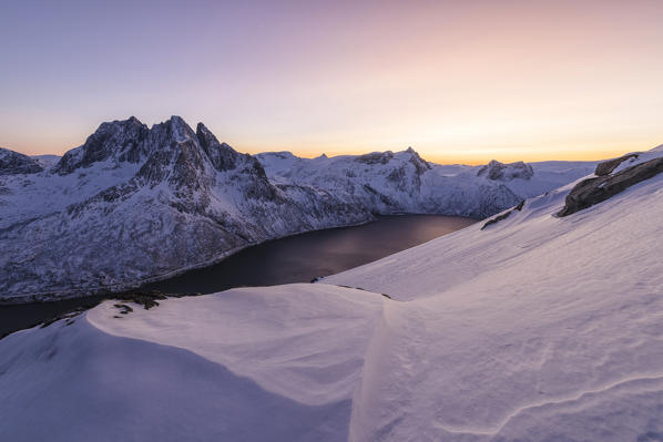 Sunset lights up the snowy peak of Mount Breidtinden and the icy sea along the Mefjorden Berg Senja Tromsø Norway Europe