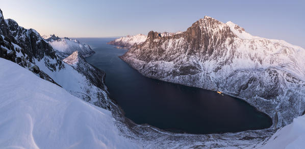 Top view of the snowy peaks surrounding Fjordgard framed by the frozen sea at sunset Ornfjorden Senja Tromsø Norway Europe