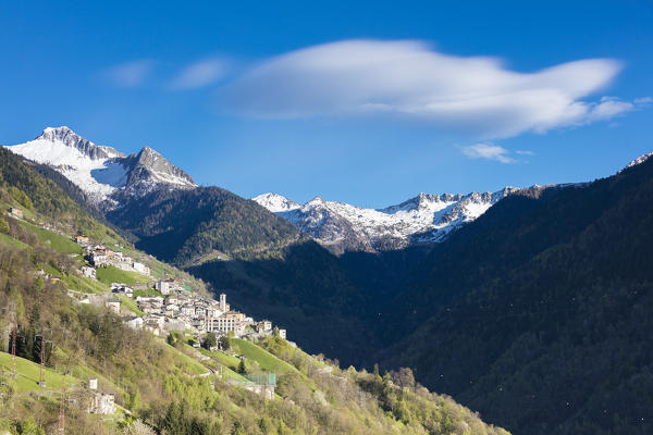 Typical alpine village framed by meadows and snowy peaks in spring Albaredo Valley Orobie Alps Valtellina Lombardy Italy Europe