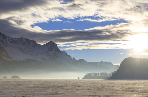 Clouds and mist at sunset on Lake Sils covered with snow Maloja Canton of Graubunden Engadin Switzerland Europe