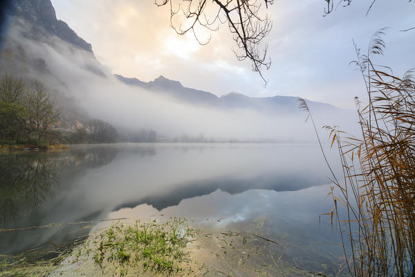 Mountains reflected in water at dawn shrouded by mist Pozzo di Riva Novate Mezzola Chiavenna Valley Lombardy Italy Europe